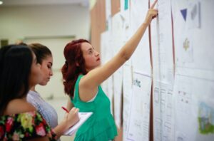 Student showing students paper on wall.