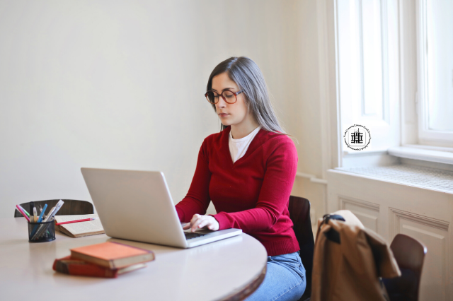 Woman with a red sweater working on her computer from home